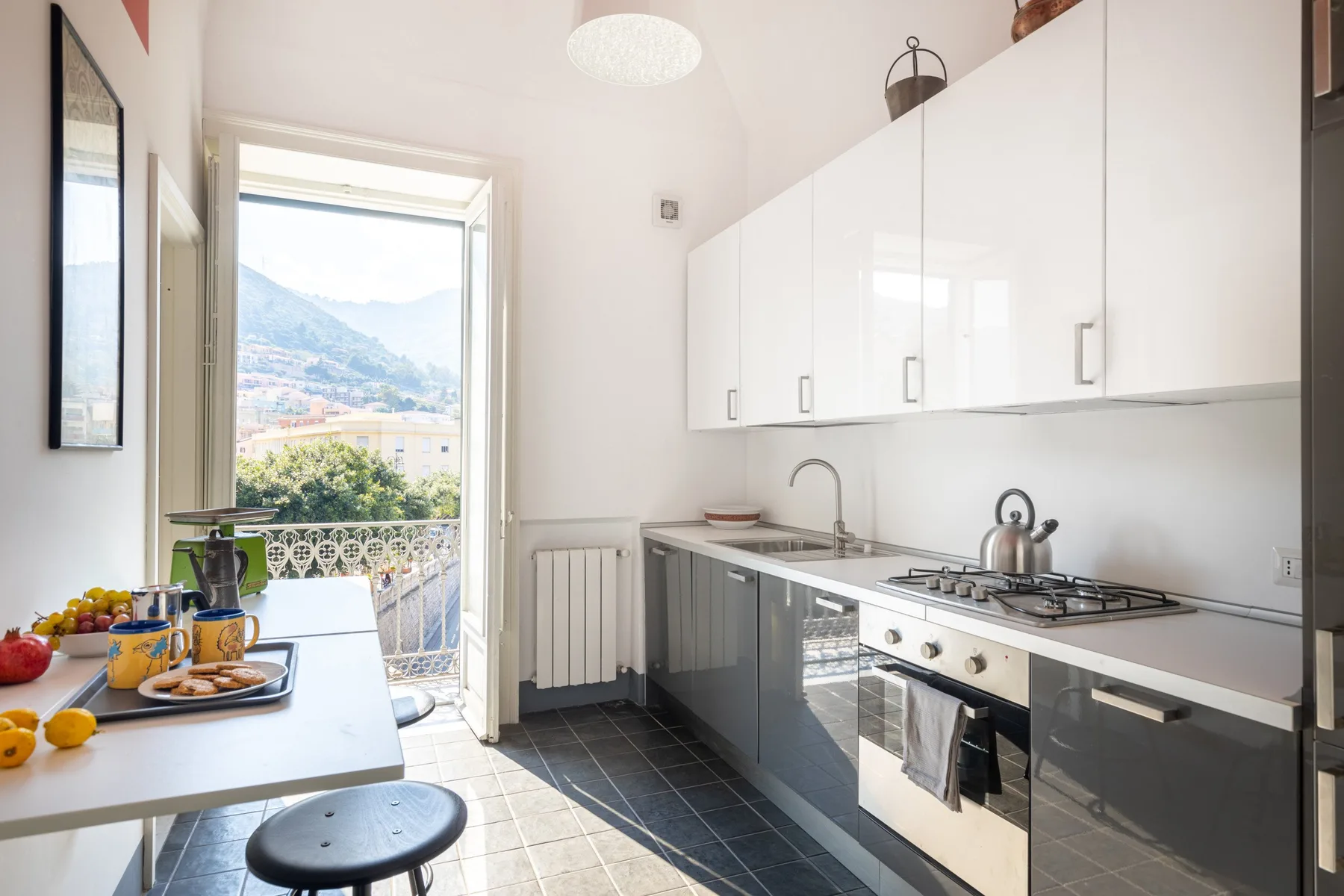 Una cocina luminosa con gabinetes blancos, una estufa de gas y una mesa.
