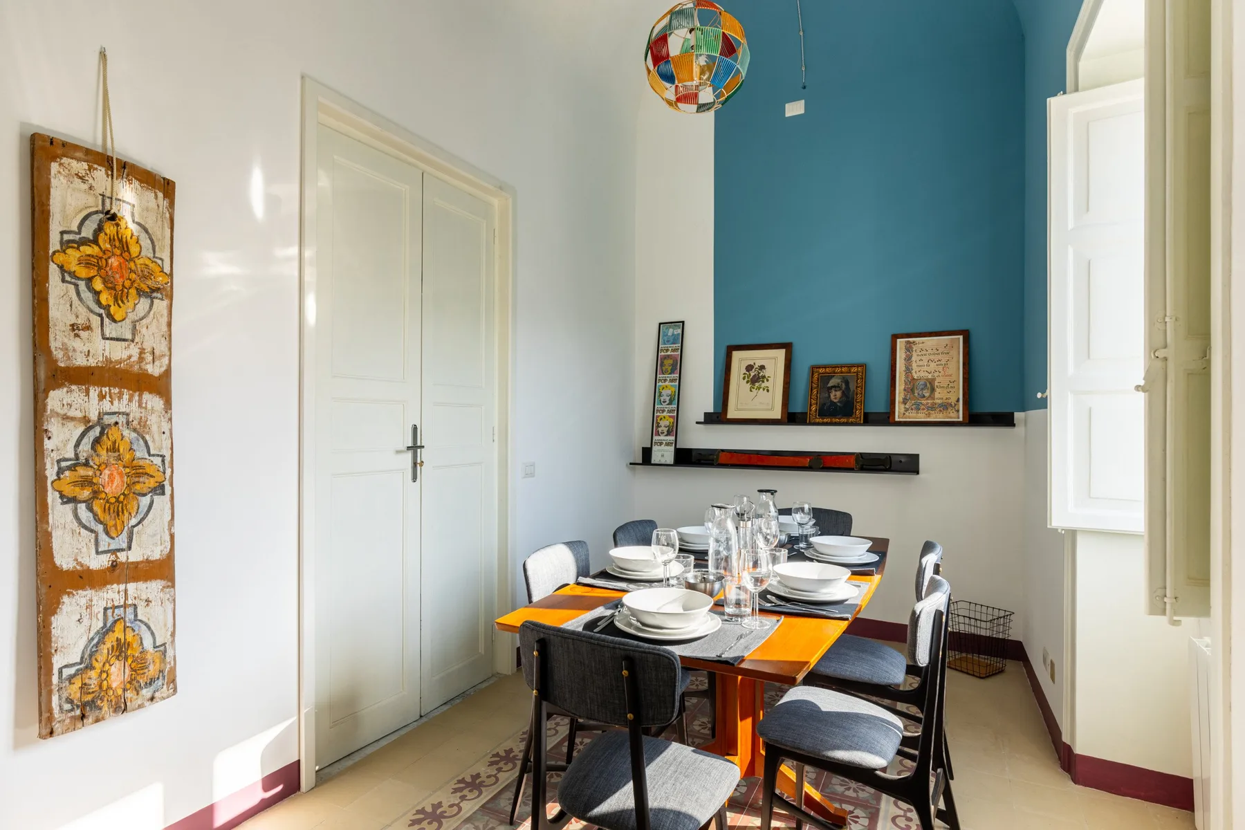 A dining area with a set table against a blue accent wall.