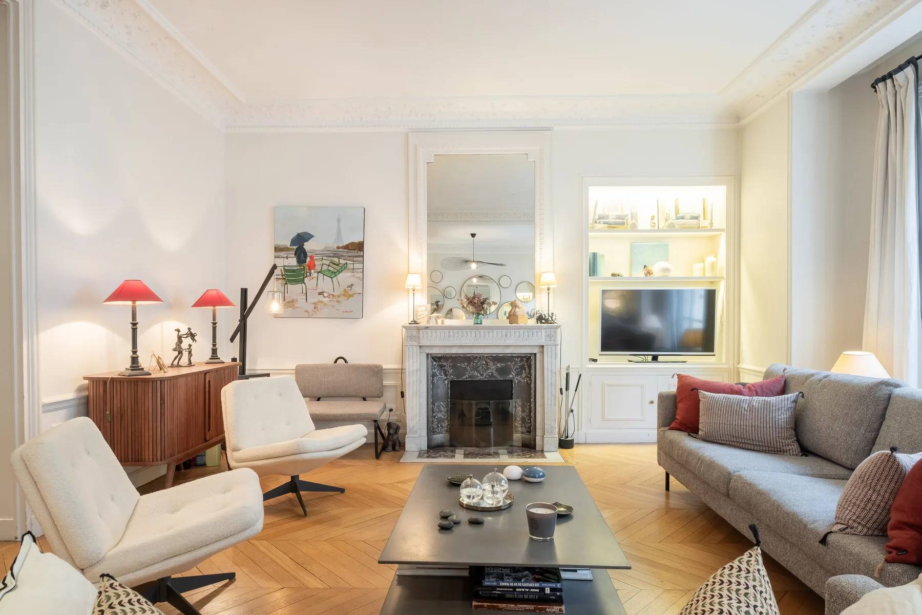A bright living room with seating arranged around a central fireplace.