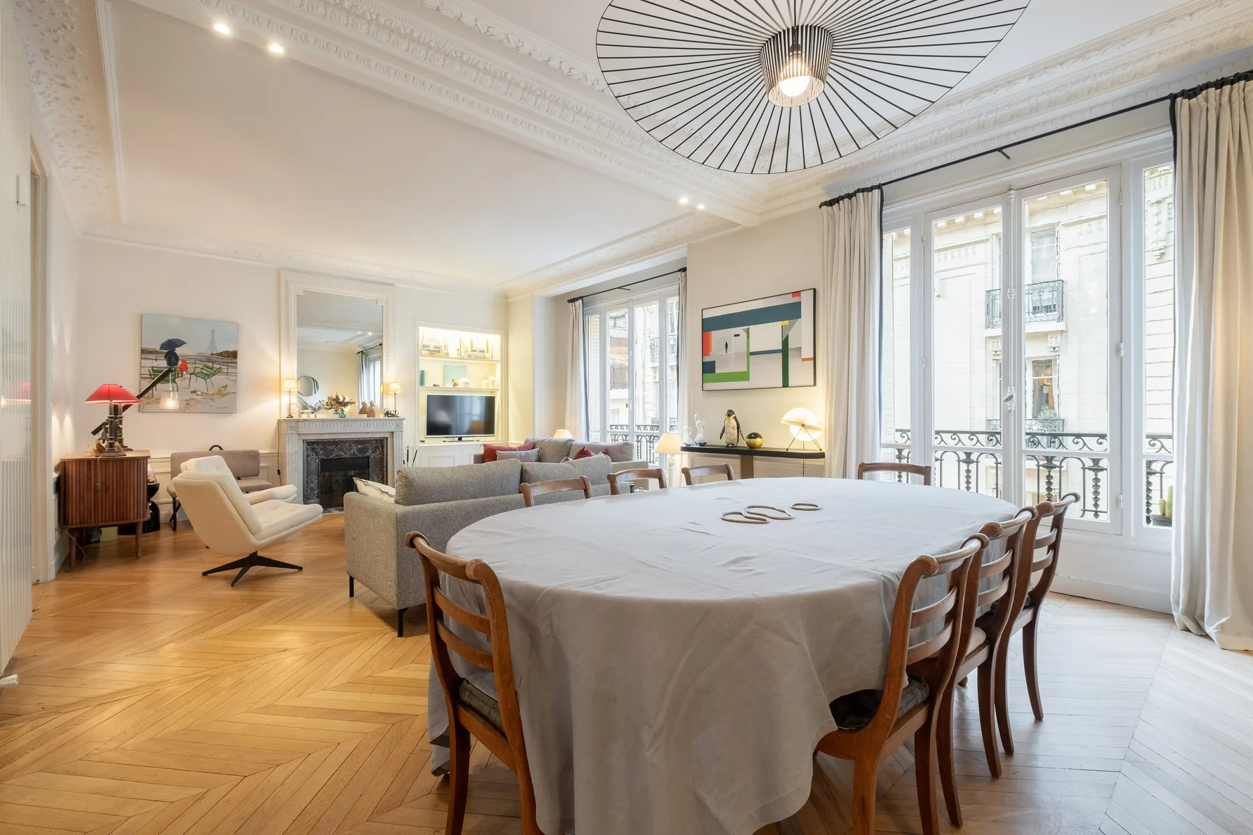 A bright dining room with a large table beside tall windows.