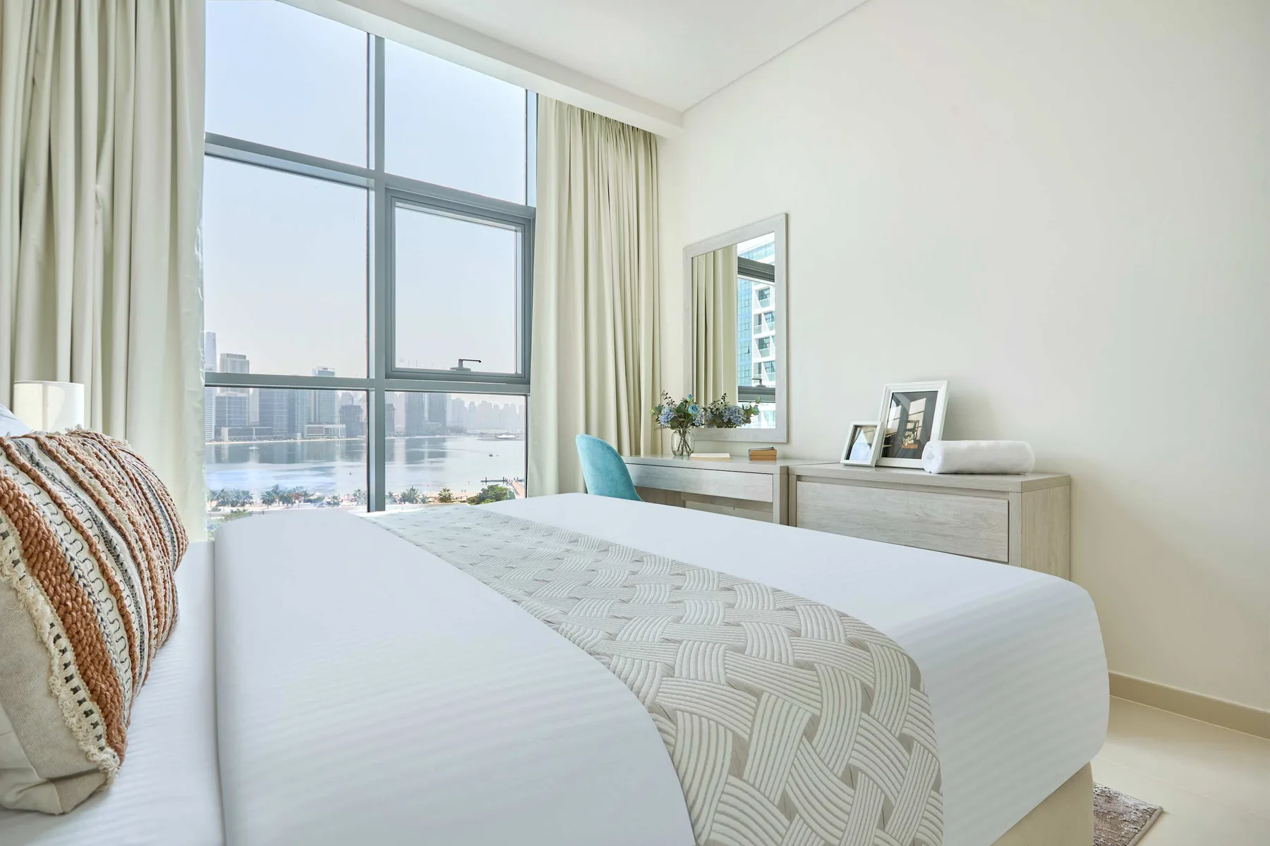 Un dormitorio luminoso con una gran ventana con vistas al agua.