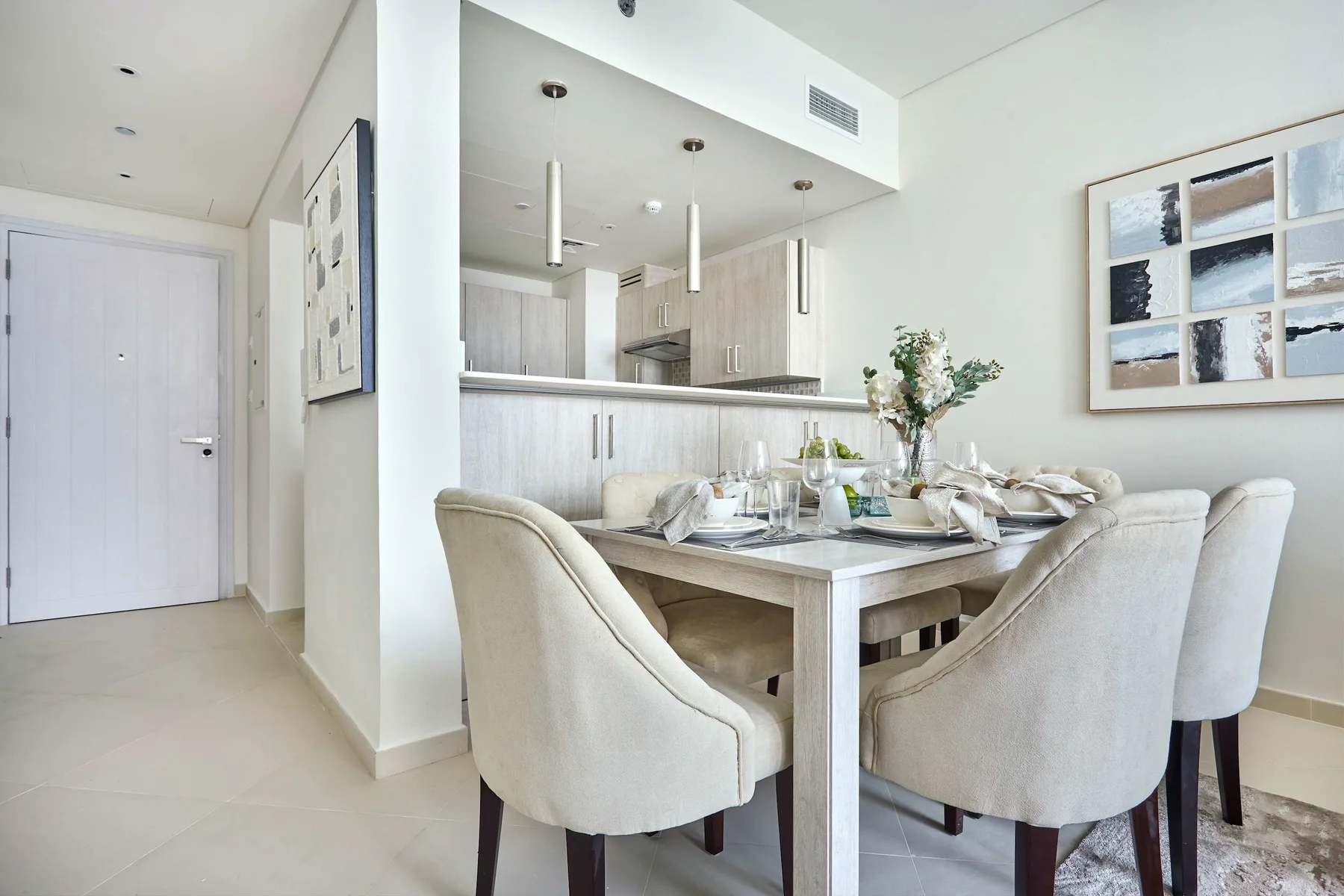 Un comedor luminoso con la mesa puesta y asientos tapizados.