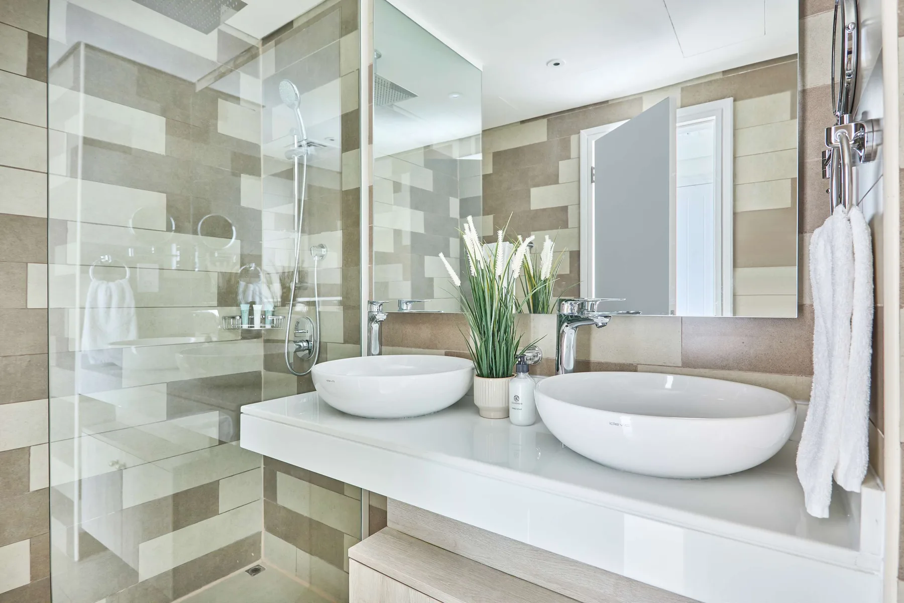 Un baño moderno con ducha de vidrio y lavabo doble.
