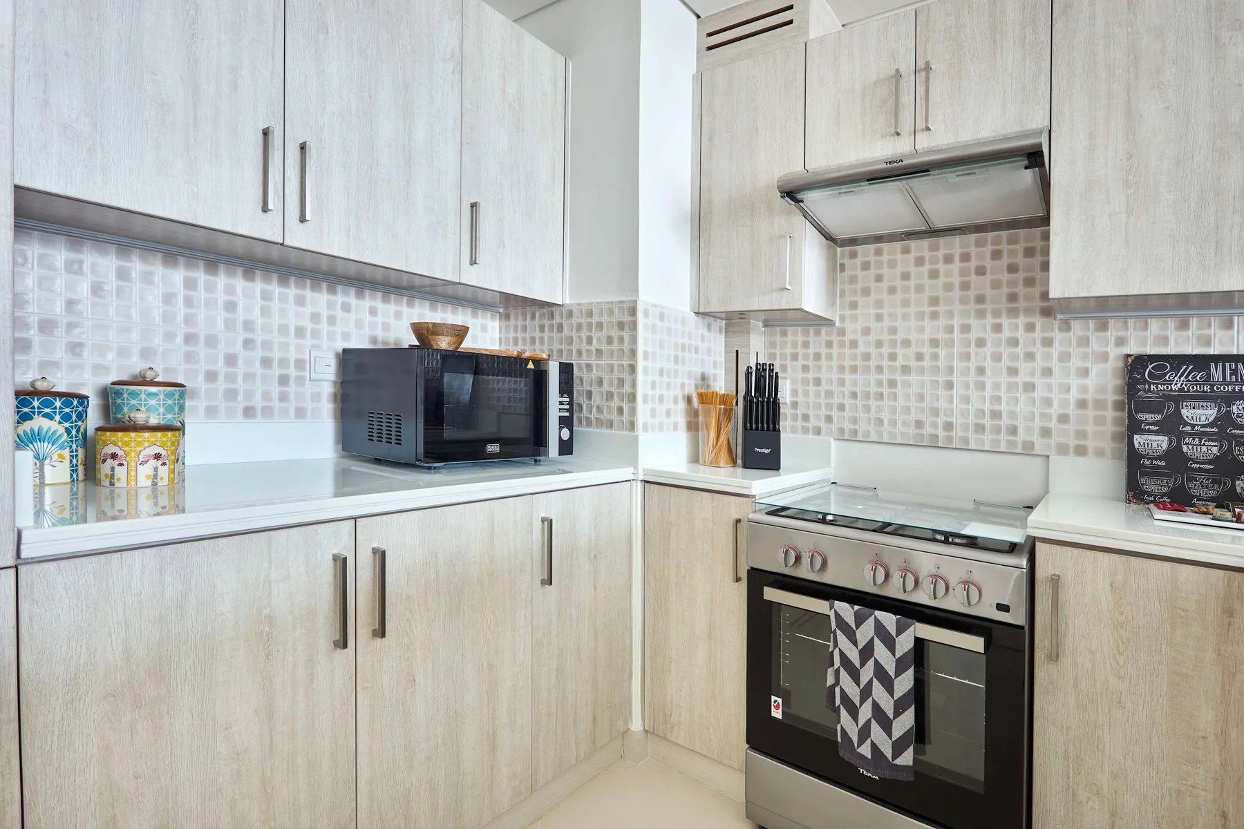 Una cocina luminosa con gabinetes claros, un salpicadero de azulejos y una estufa.