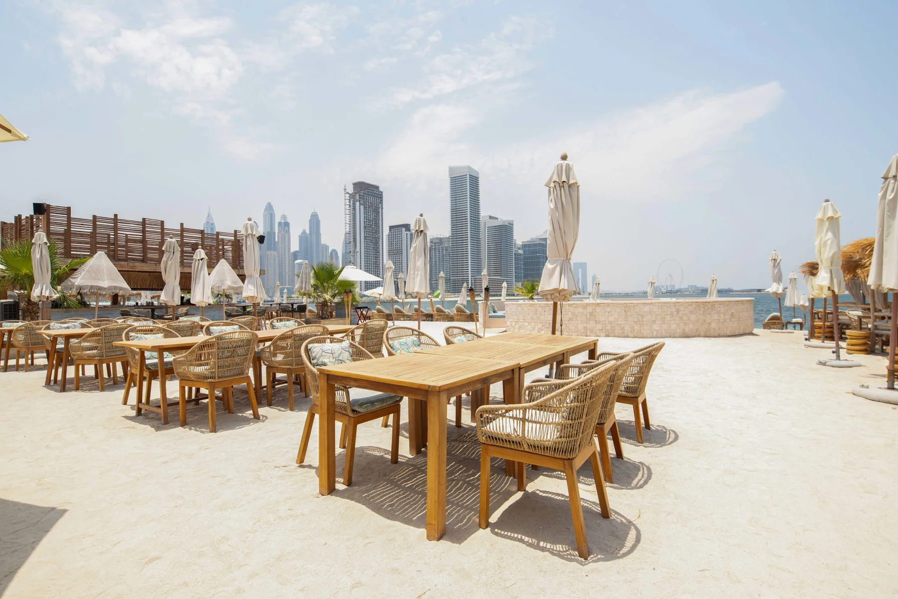 Una terraza de comedor al aire libre con mesas y asientos da a un horizonte urbano.