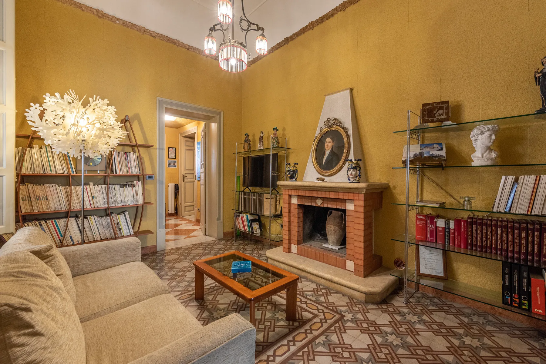 A warmly colored living room with seating, bookshelves, and a fireplace.