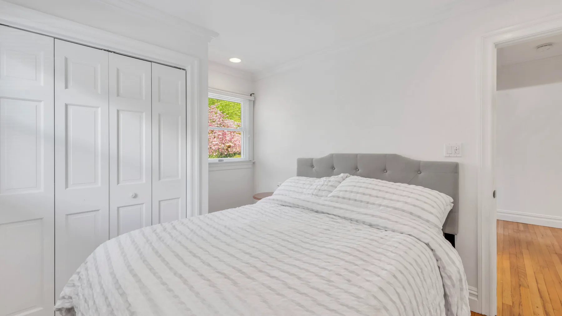 Un dormitorio luminoso con una cama y puertas de armario blancas.