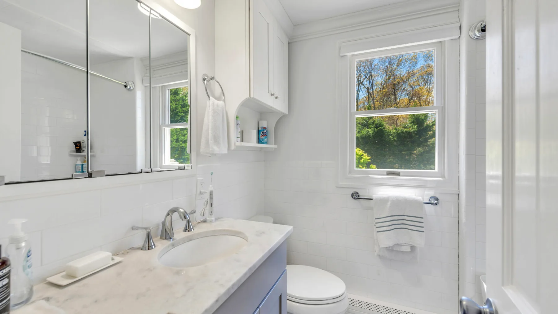 Un baño luminoso con lavabo, tocador con espejo e inodoro.