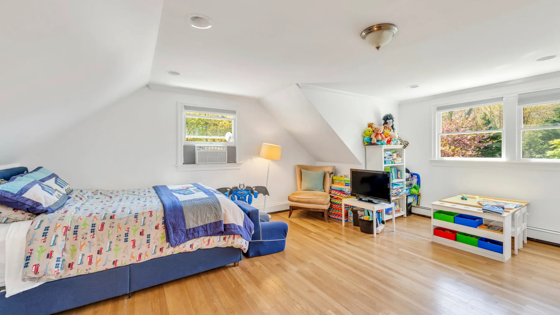 Un dormitorio luminoso en el ático con una cama, asientos y una zona de juegos.