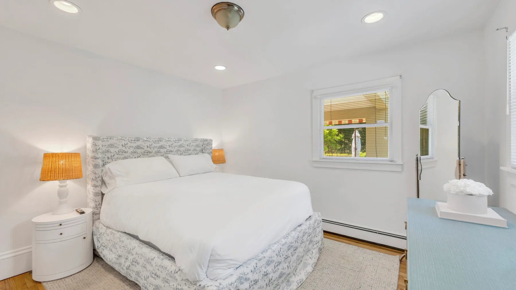 Un dormitorio luminoso con una cama bien tendida y una ventana.