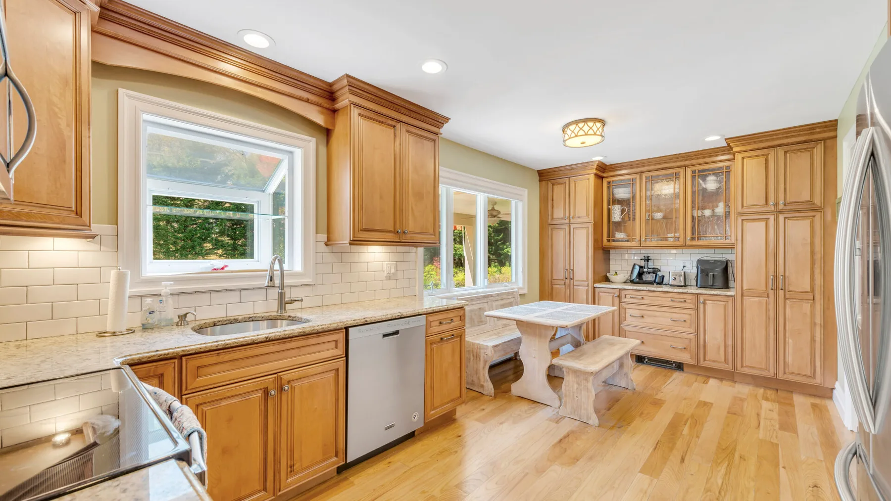 Una cocina luminosa con gabinetes de madera, un salpicadero de azulejos y una mesa pequeña.