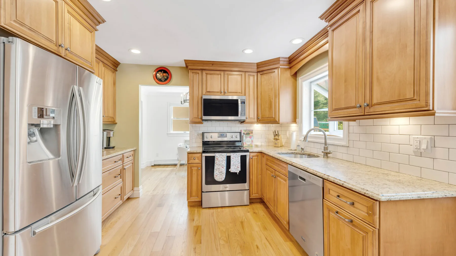 Una cocina luminosa con gabinetes de madera, electrodomésticos de acero inoxidable y una encimera larga.