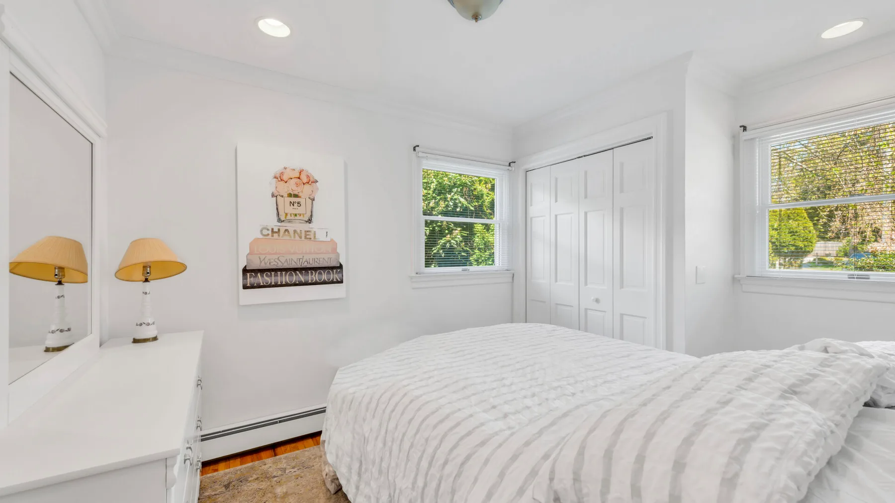 Un dormitorio luminoso con una cama y ventanas con vistas a la vegetación.