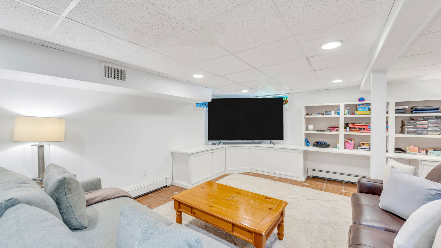 Una sala luminosa con asientos, una mesa de centro de madera y un televisor en la pared.