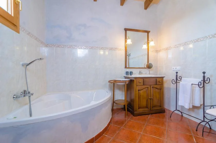 Un baño con bañera, tocador de madera y espejo.