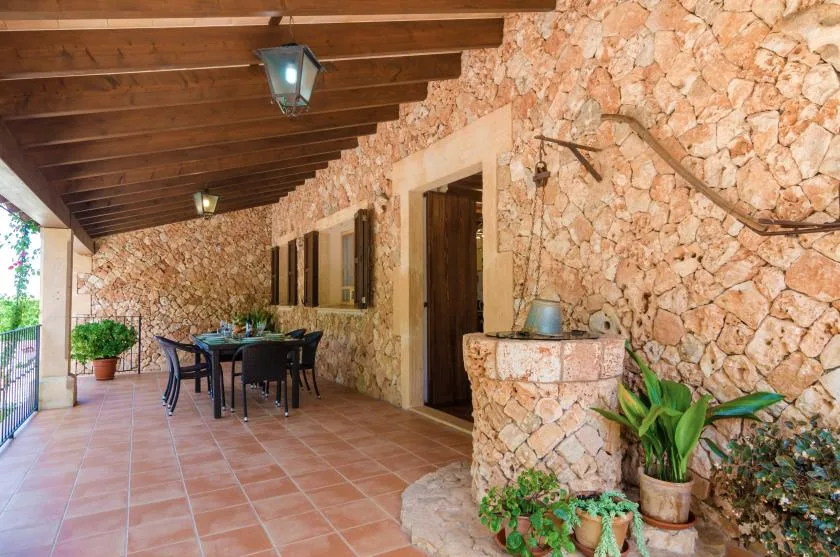 Un patio cubierto de piedra con suelo de baldosas y mesa de comedor al aire libre.
