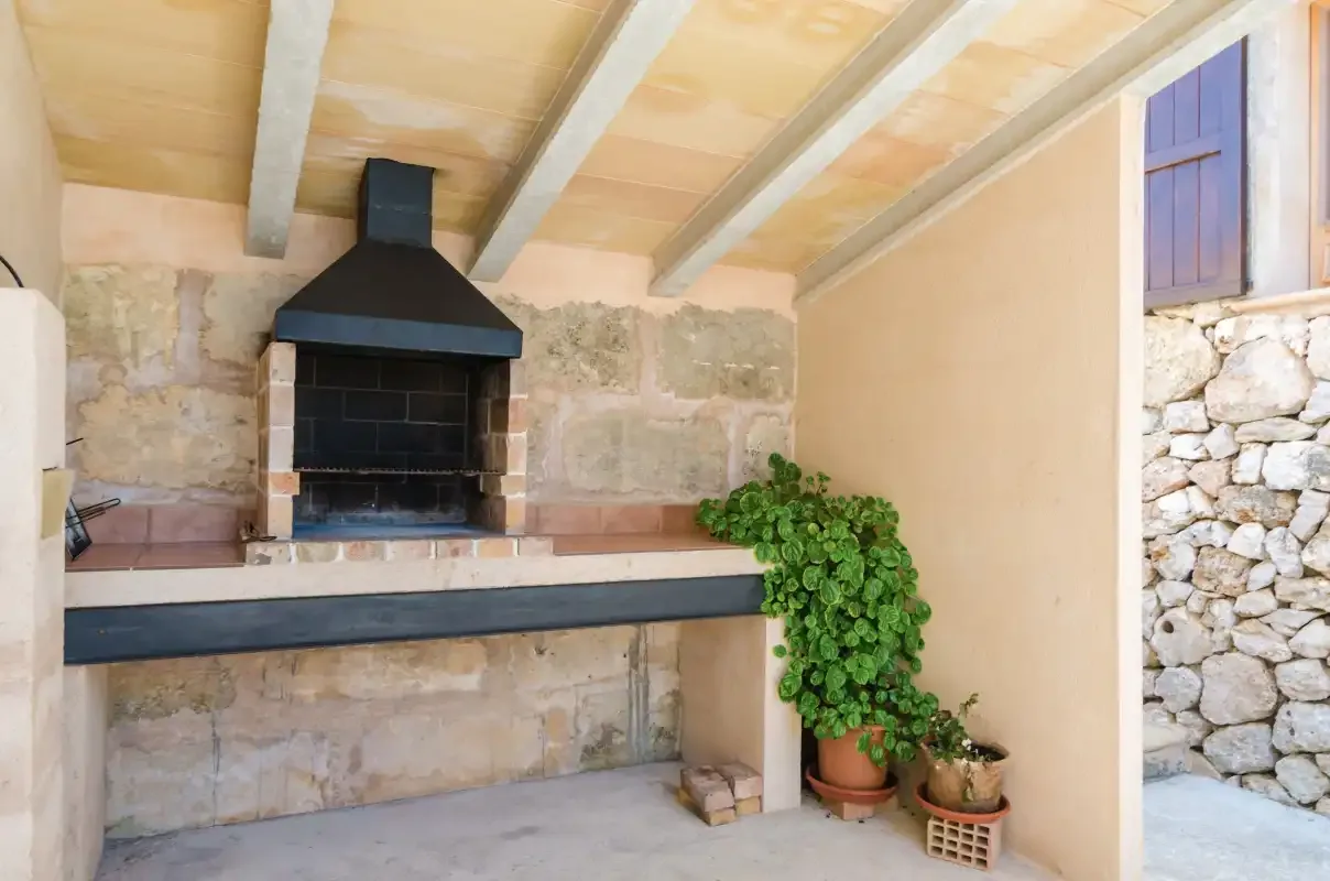 Una zona de barbacoa al aire libre con parrilla y plantas en macetas.