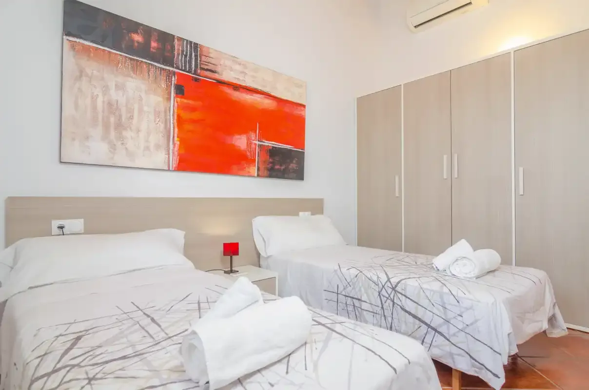 Un dormitorio con dos camas, ropa de cama estampada y un armario grande.