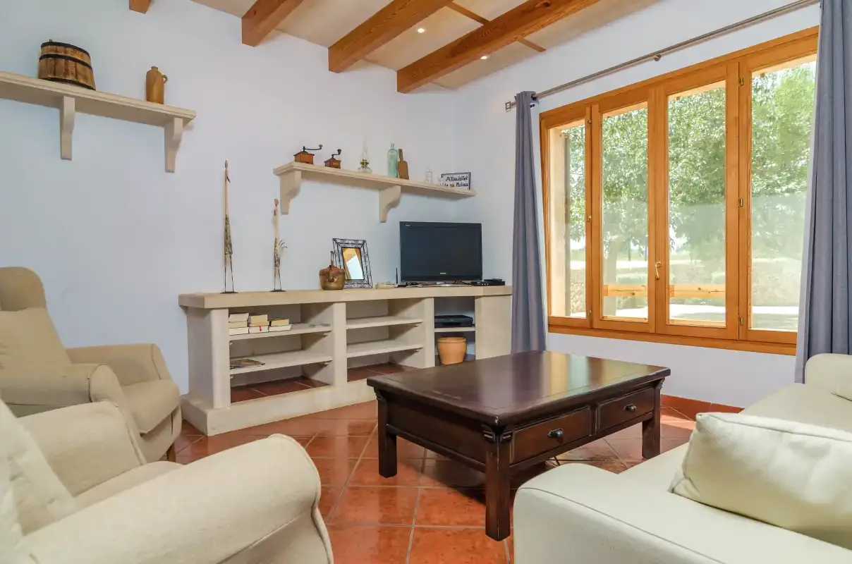 Una sala de estar con asientos, una mesa de centro y grandes ventanas.