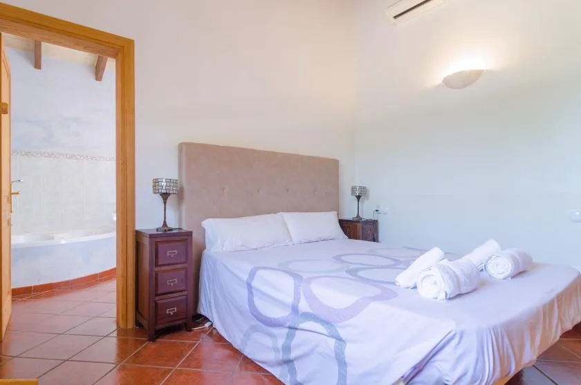 Un dormitorio con una cama, mesitas de noche y una puerta abierta a un baño.
