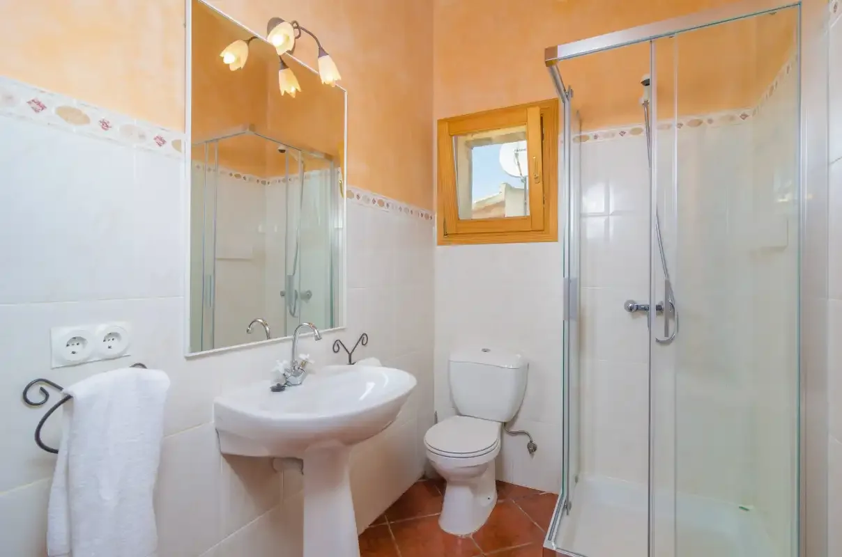 Un baño con lavabo de pedestal, inodoro y ducha de vidrio.