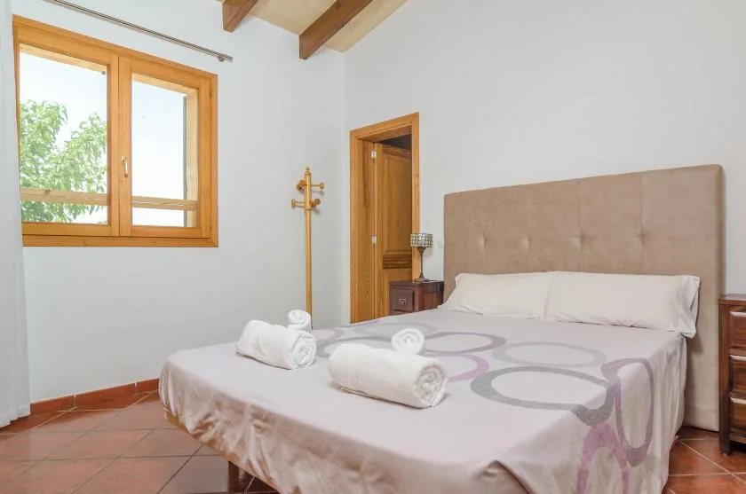 Un dormitorio con una cama doble, ropa de cama estampada y una ventana con marco de madera.