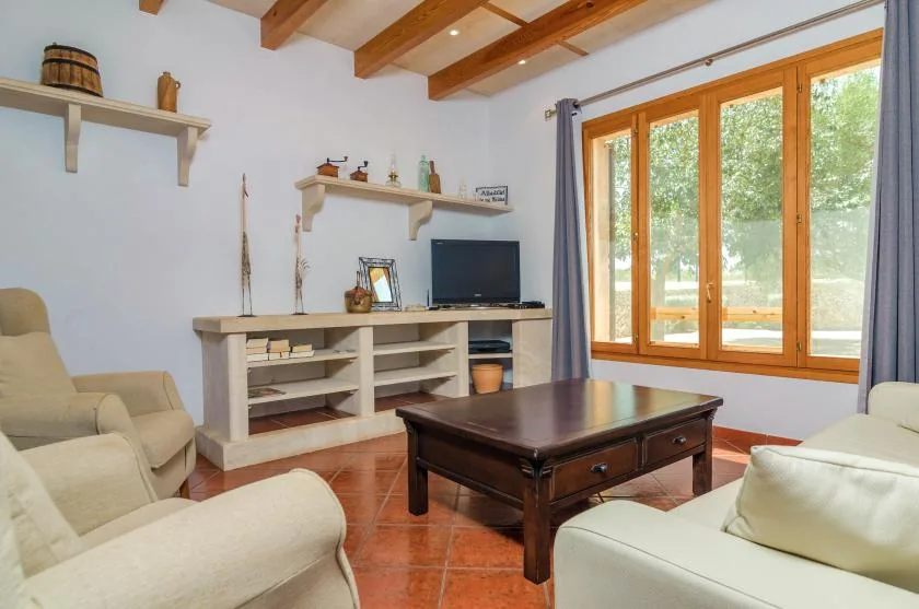 Una sala de estar con asientos claros, una mesa de centro oscura y grandes ventanas.