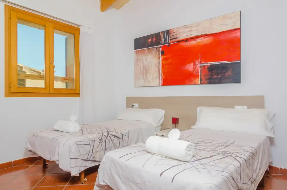 Un dormitorio con dos camas y una pintura abstracta sobre los cabeceros.