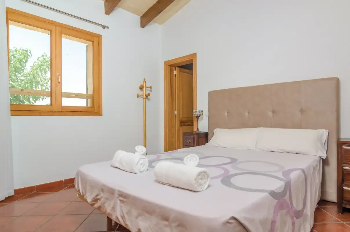Un dormitorio con una cama doble y una ventana con vistas a la vegetación.