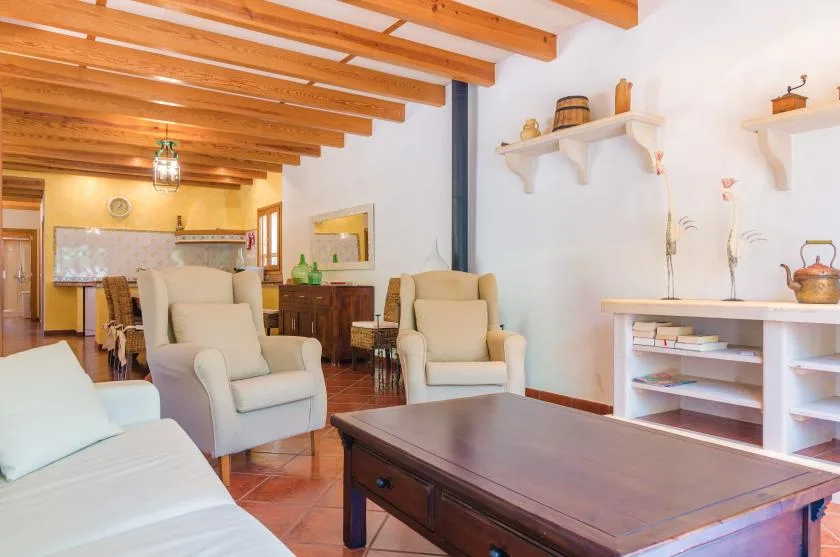 Una sala de estar con asientos tapizados, una mesa de centro de madera y vigas expuestas en el techo.
