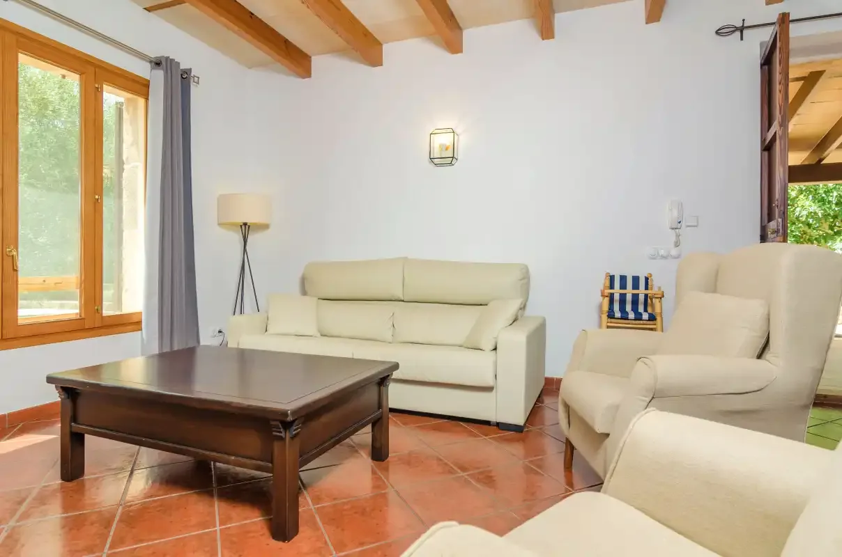 Una sala de estar con asientos claros, una mesa de centro de madera y vigas vistas.