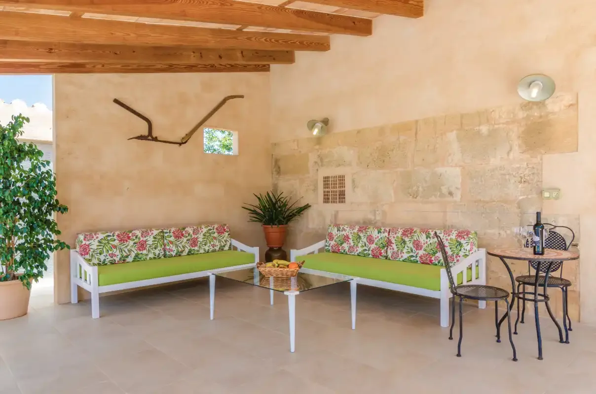 Una luminosa zona de estar interior con bancos florales y mesas pequeñas.