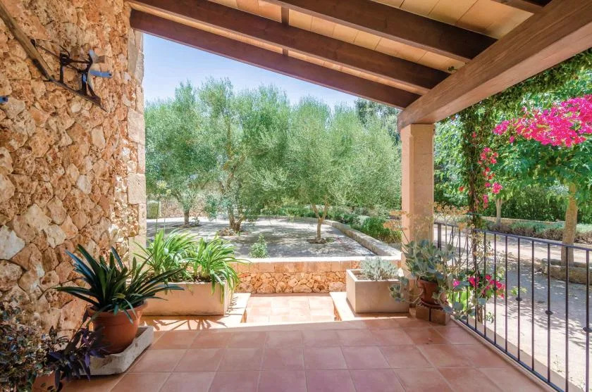 Una terraza cubierta de piedra con plantas en macetas da a un jardín.