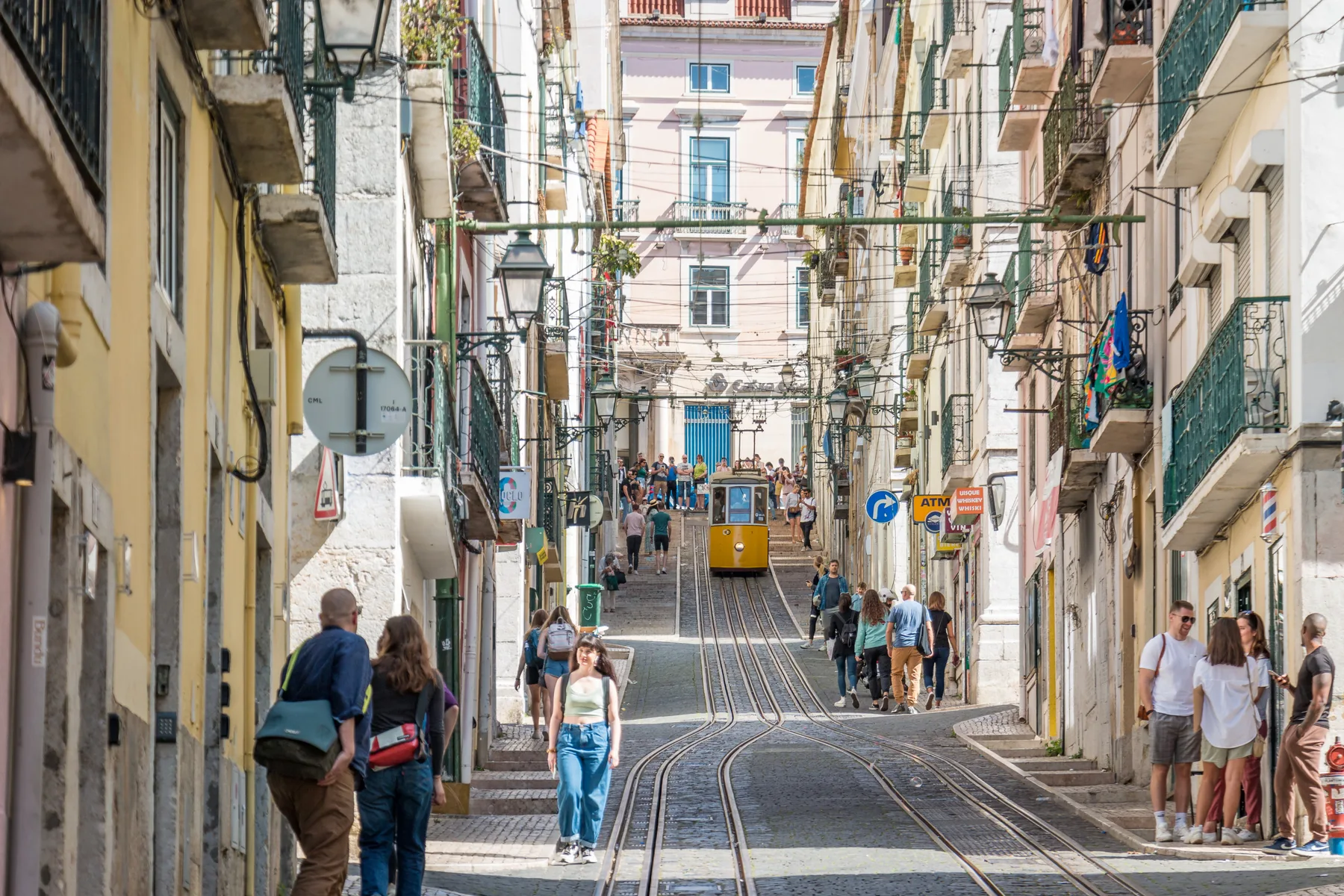 A narrow city street with tram tracks runs between closely spaced buildings.