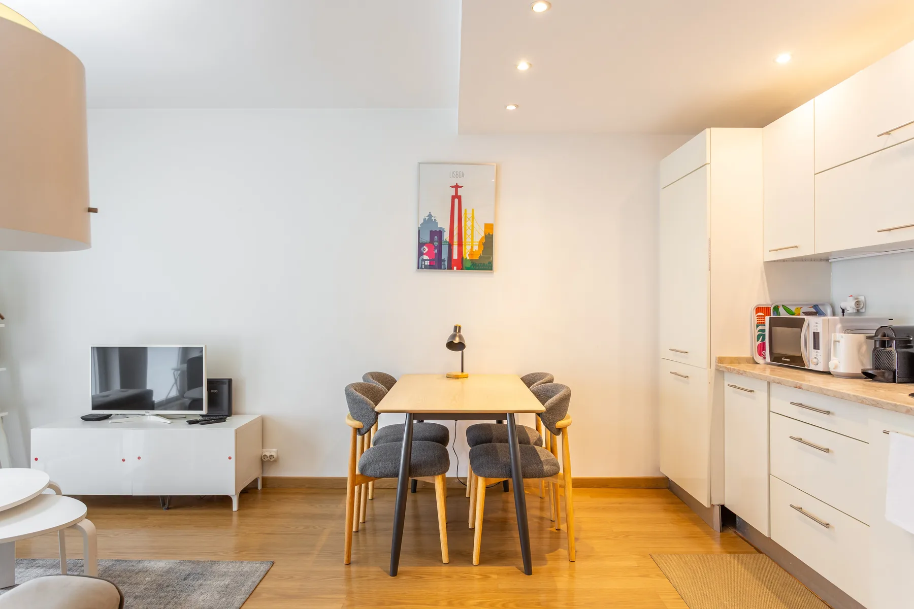 A bright dining area with a table and seating beside a compact kitchen.