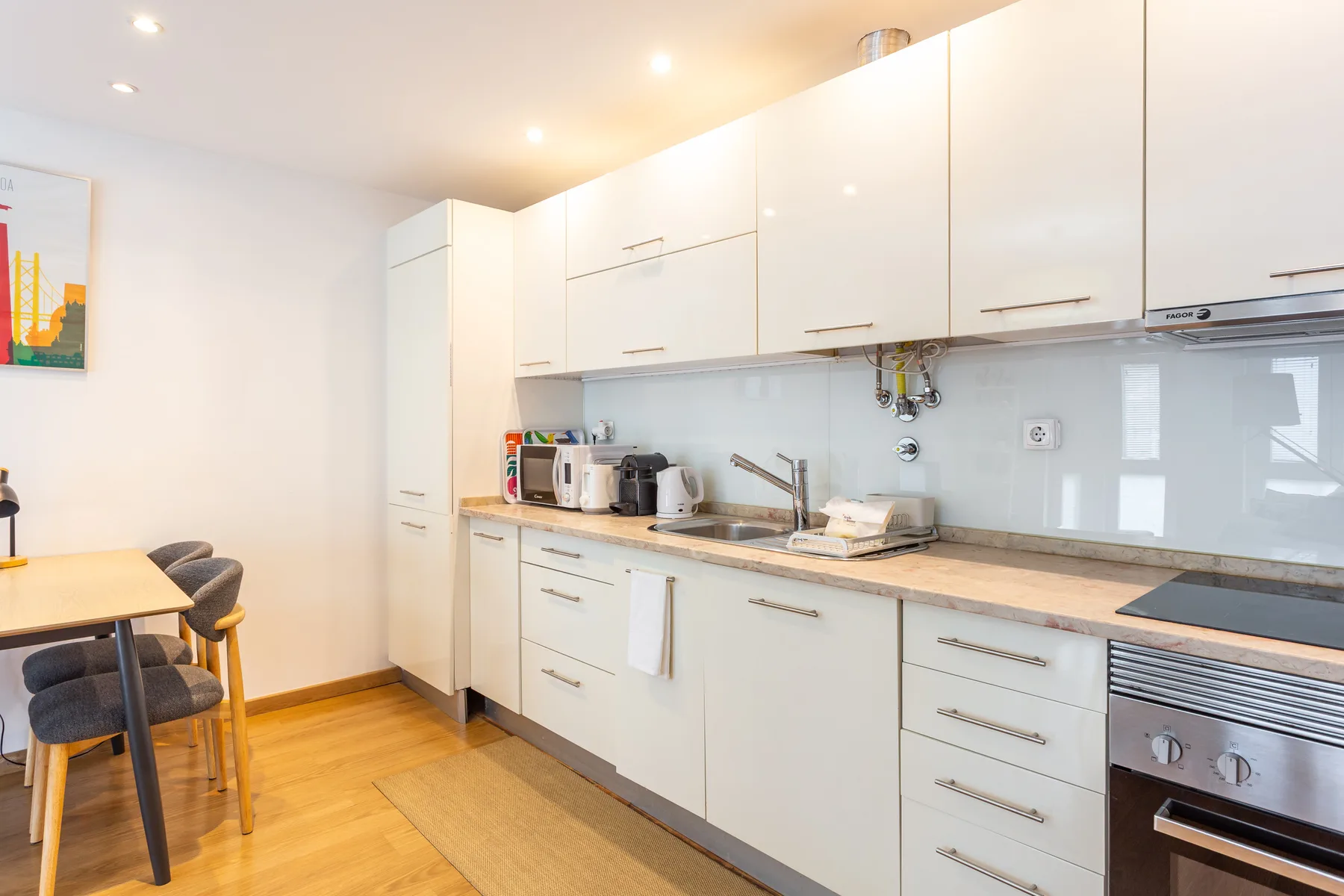 A bright kitchen with white cabinets, a countertop, and a dining table.