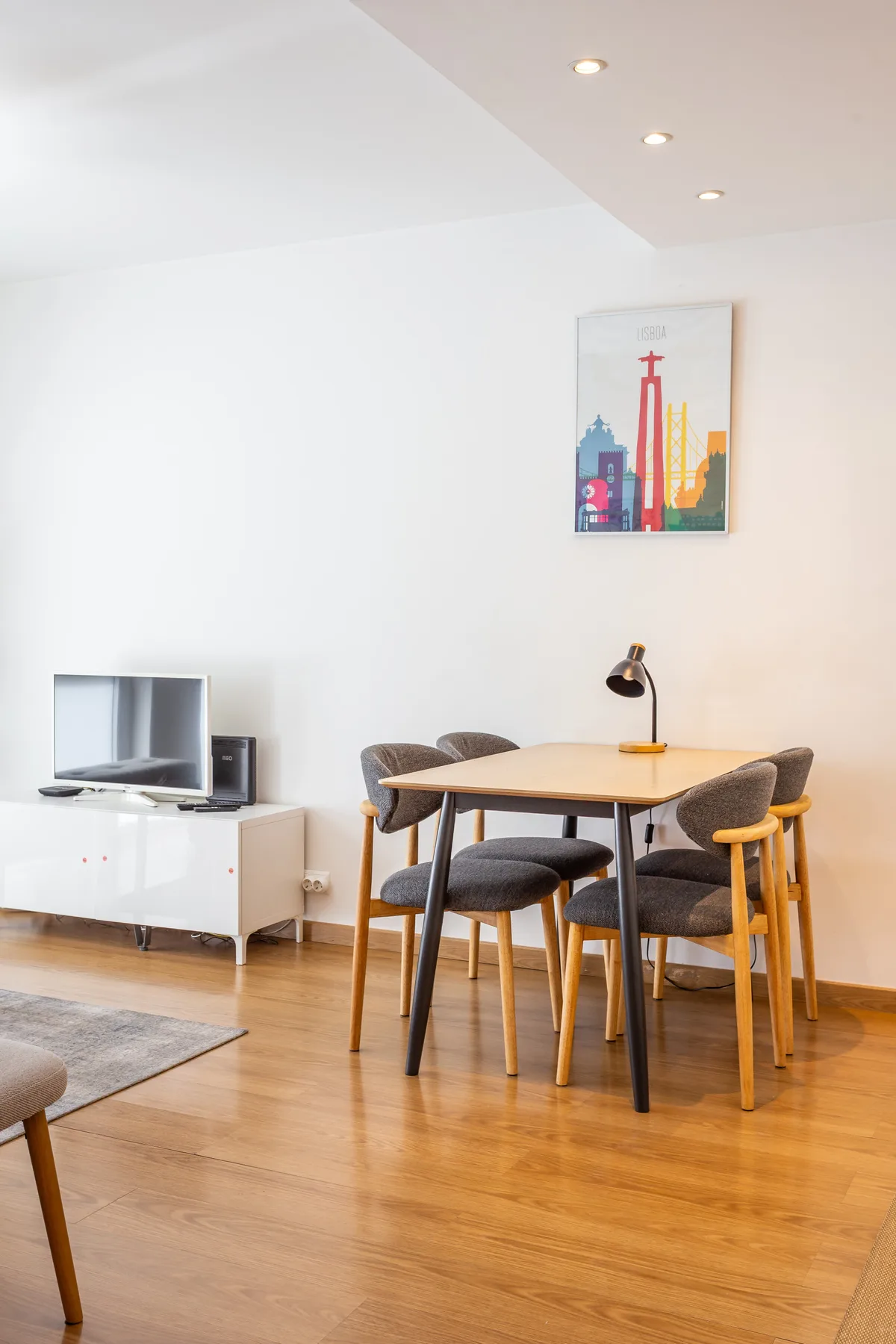 Dining area with a wooden table and chairs beside a television.
