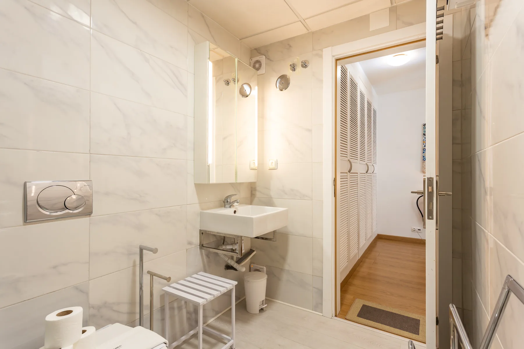 A bright bathroom with a wall-mounted sink and tiled walls.