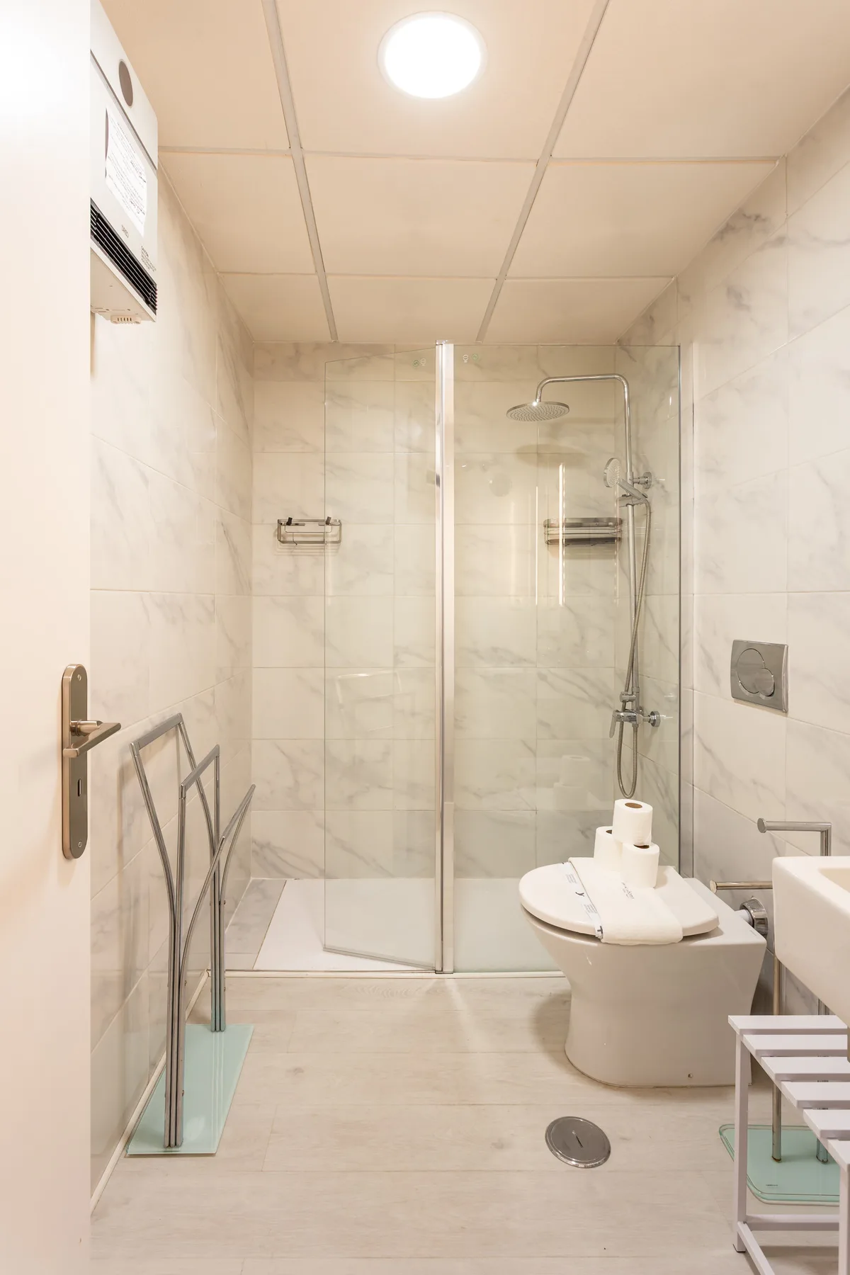 A tiled bathroom with a glass shower and a toilet.