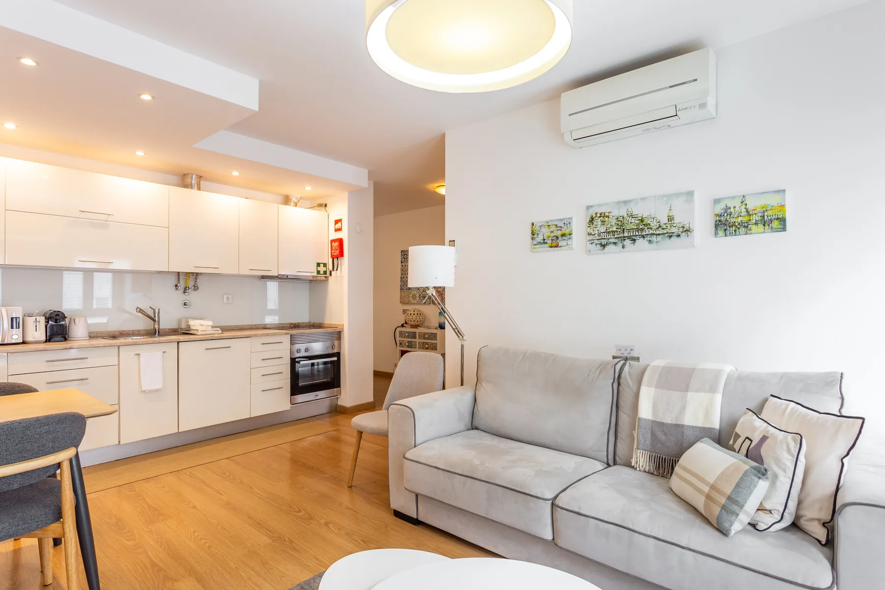 A living area with a gray sofa beside an open kitchen.