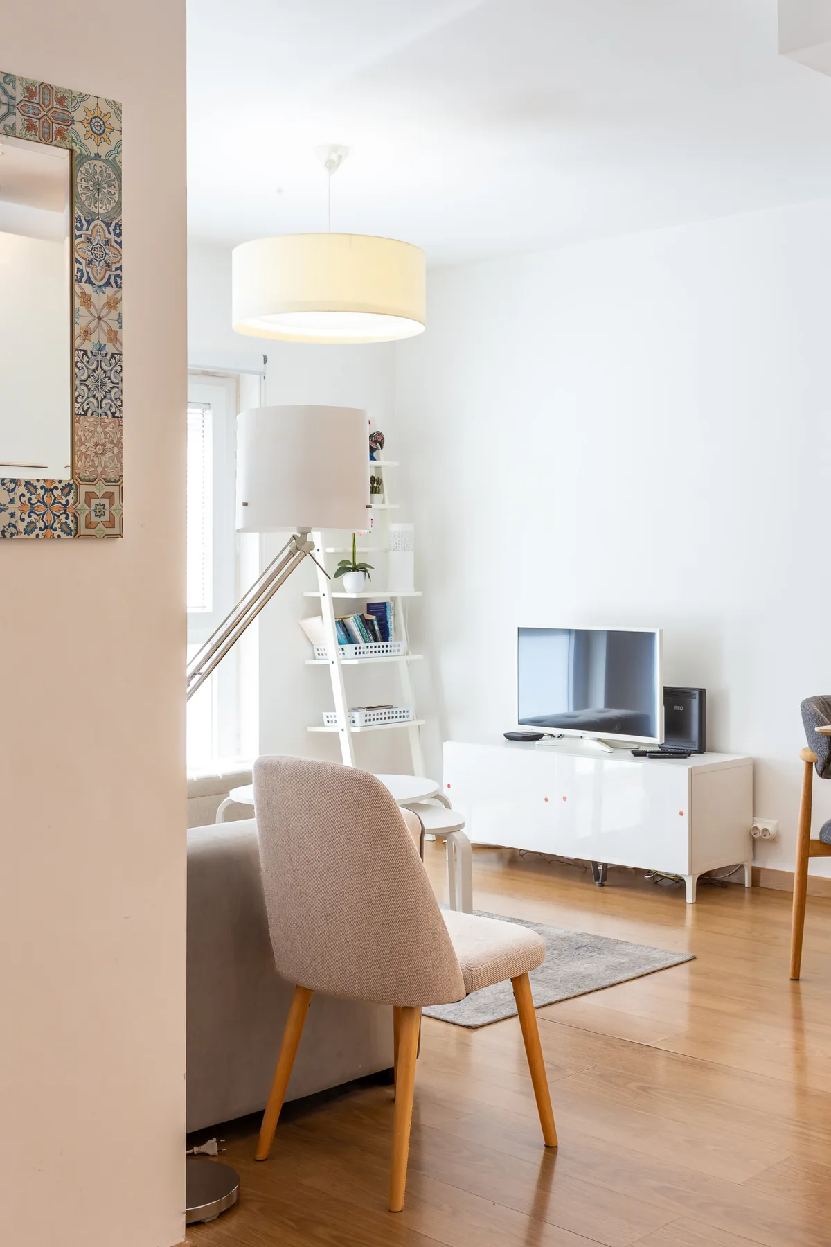 A bright living room with seating, a television, and a white media cabinet.