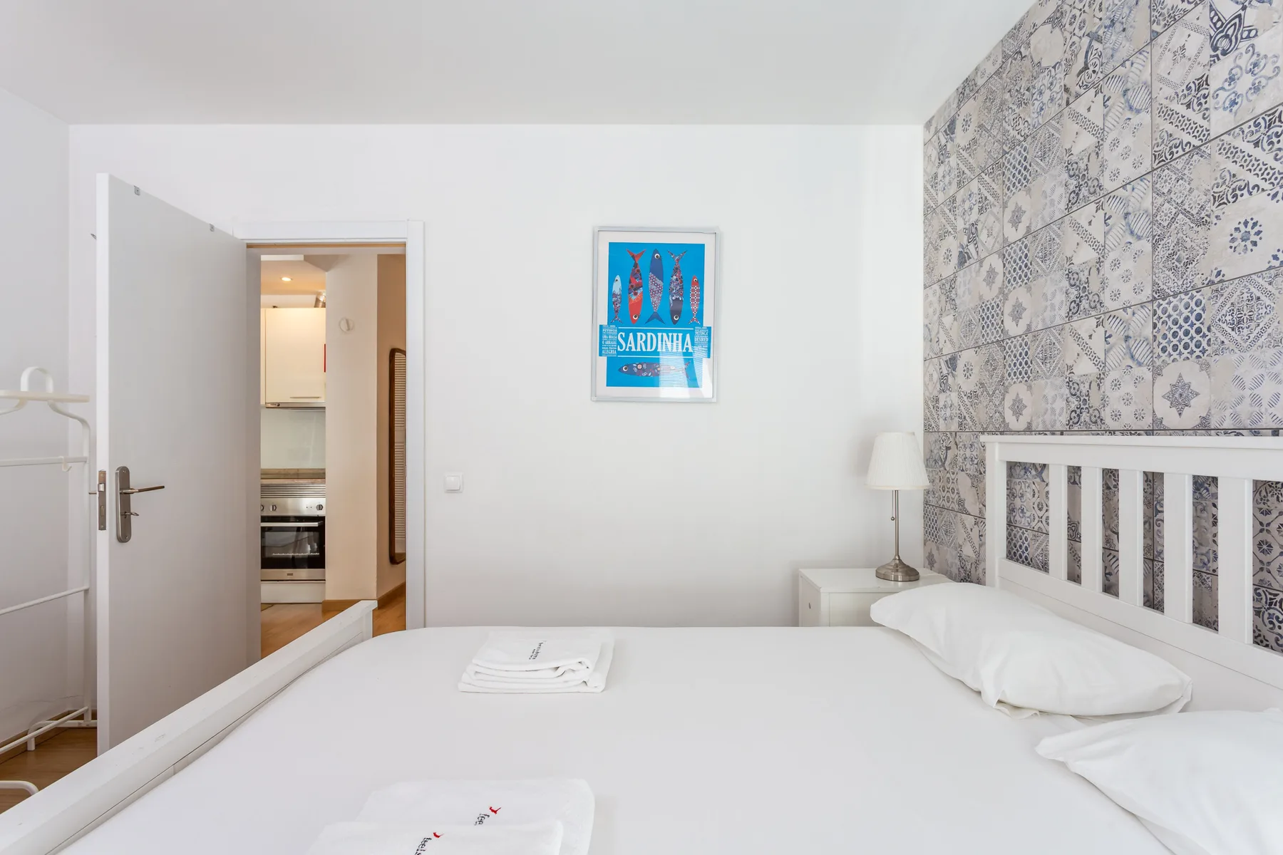 A bedroom with a neatly made bed and a patterned wall.