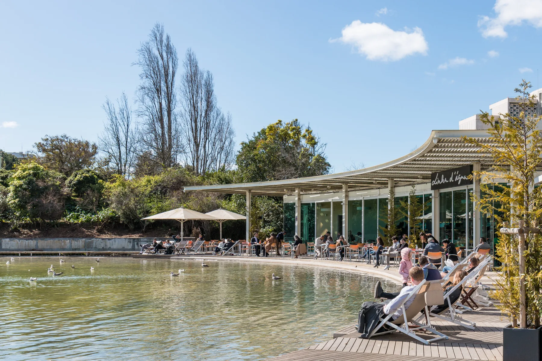 A waterside café with outdoor seating beside a pond.