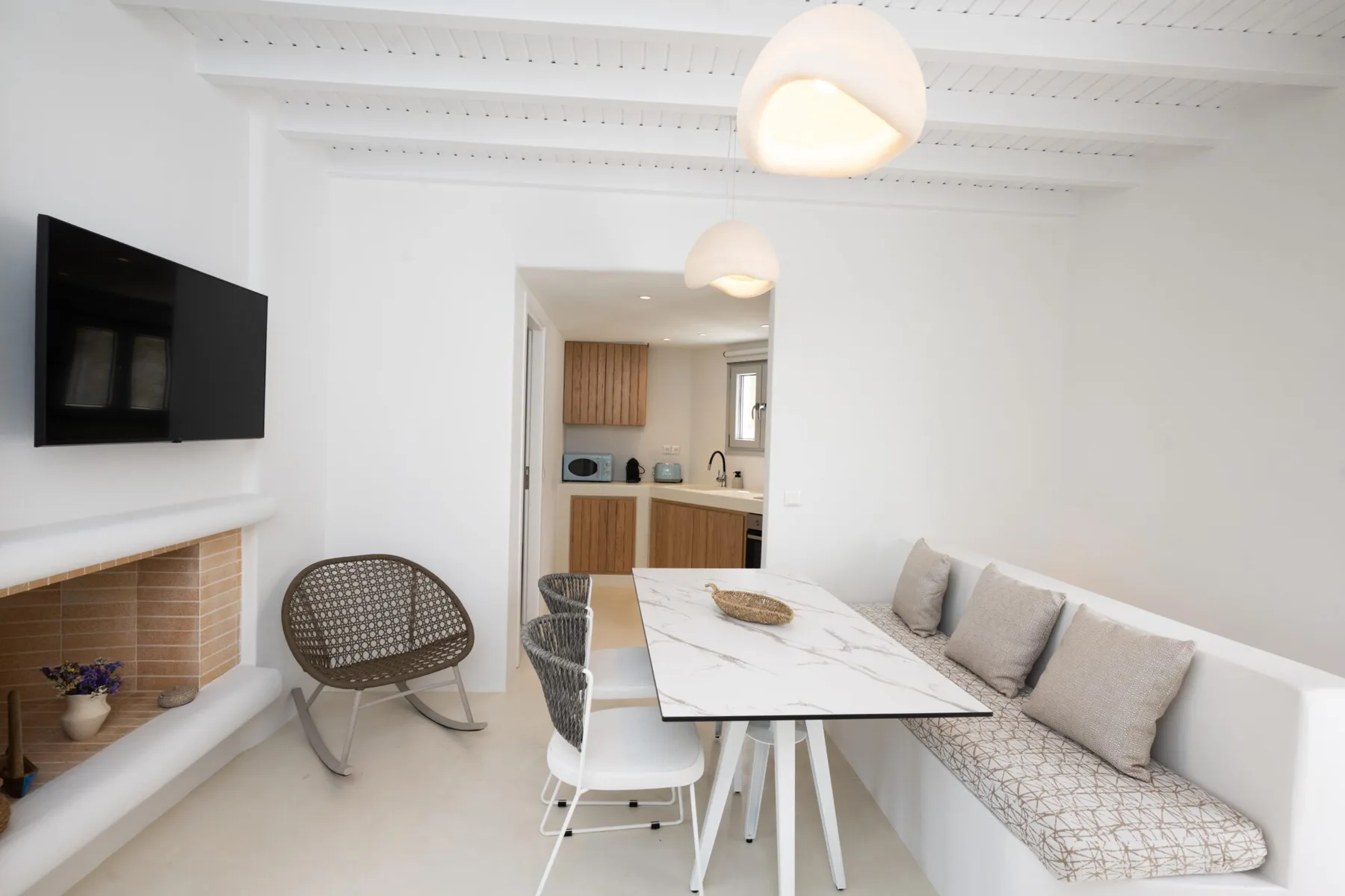 Comedor luminoso con una mesa, un banco y una cocina abierta.