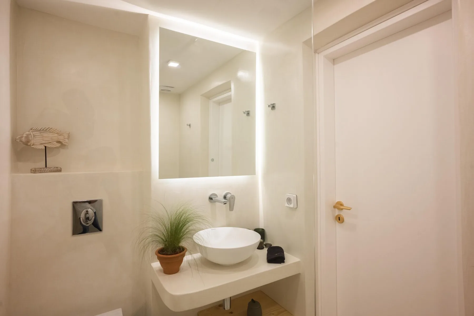 Un baño con lavabo y un espejo iluminado.