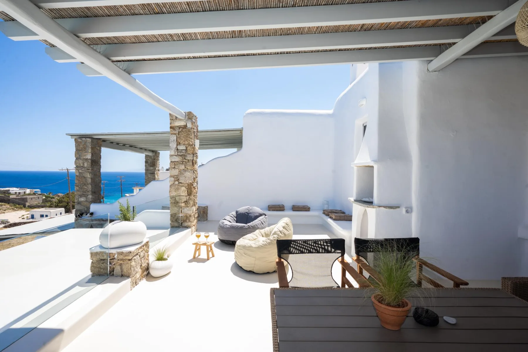 A bright outdoor terrace with lounge seating and a view of the sea.
