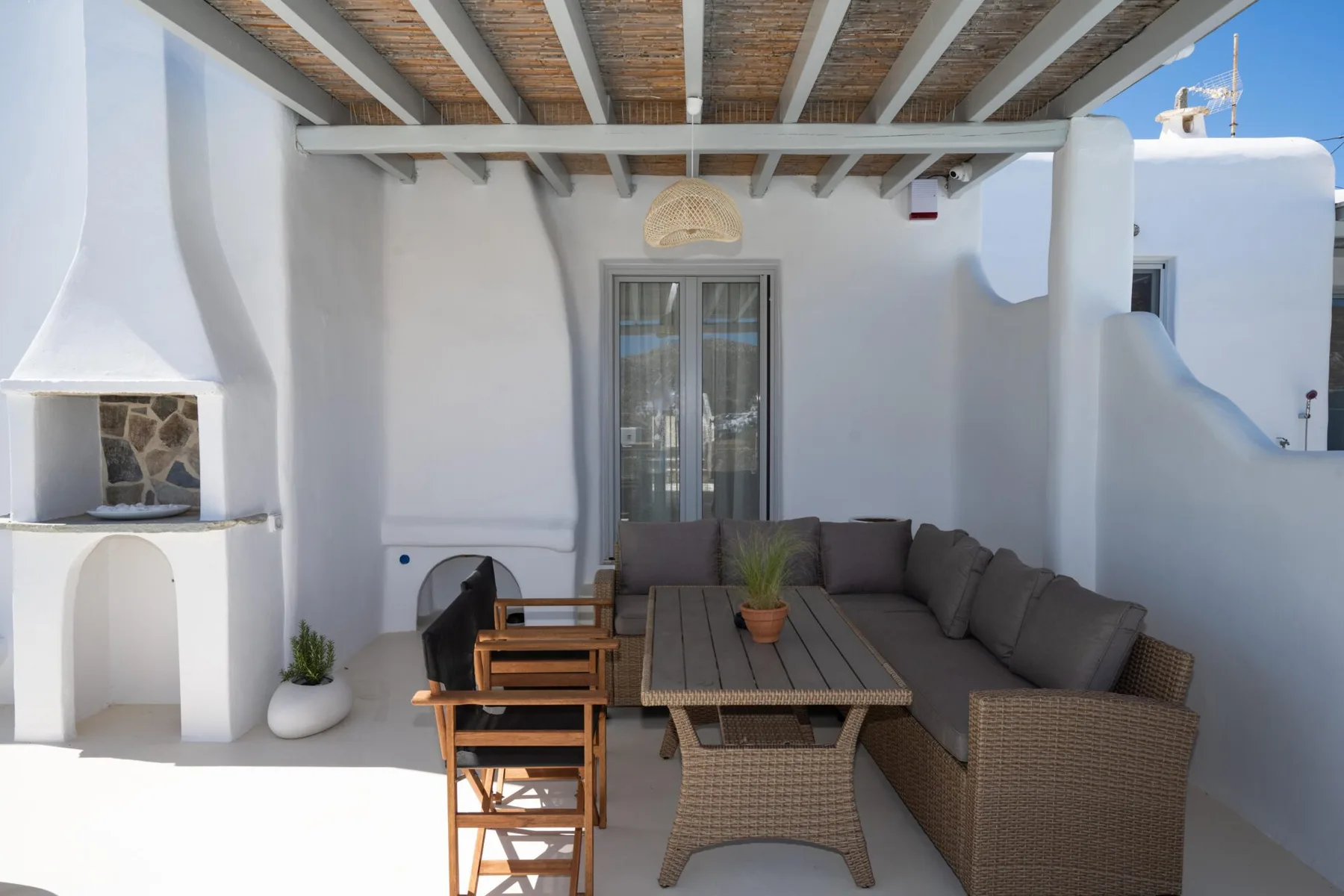 Una zona exterior de comedor y descanso con una mesa larga y asientos acolchados.
