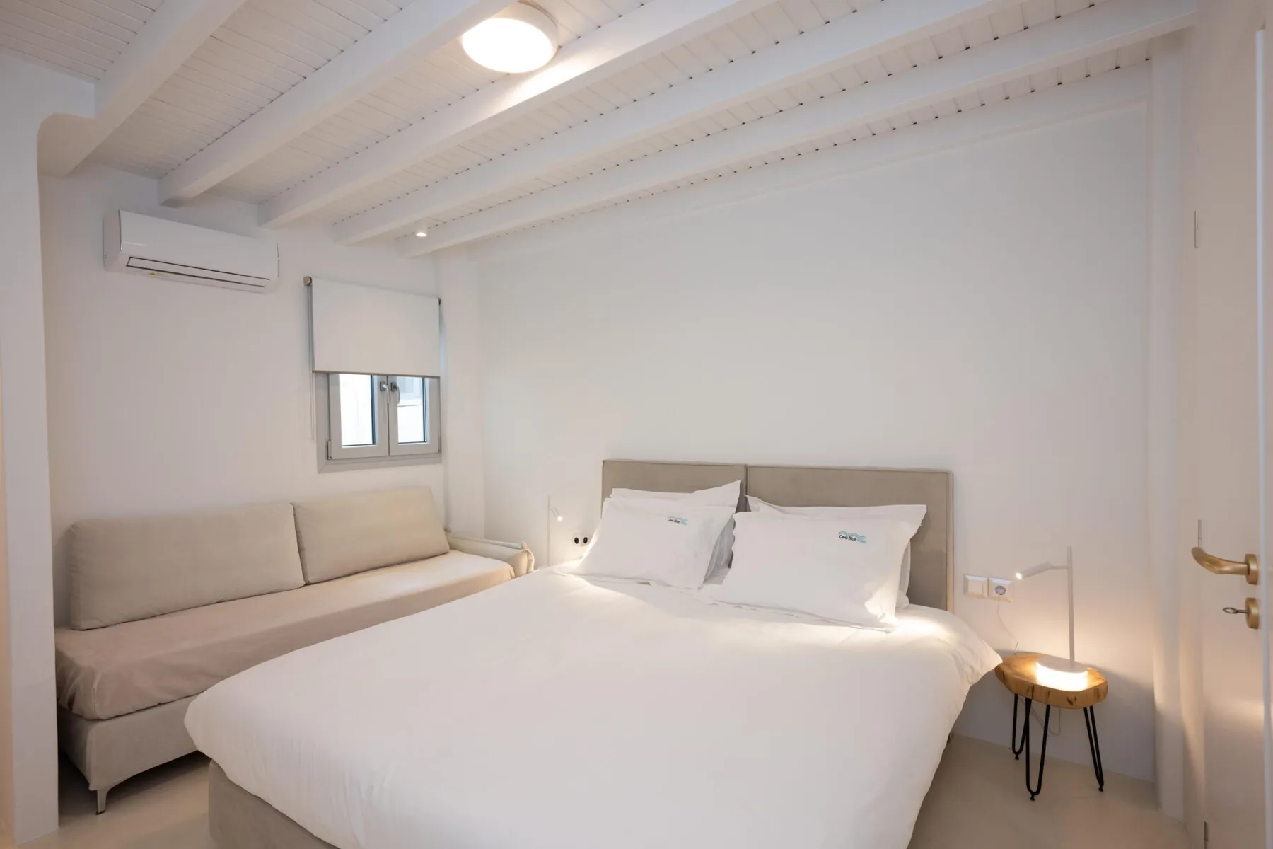 Un dormitorio luminoso con una cama grande y una pequeña zona de estar.