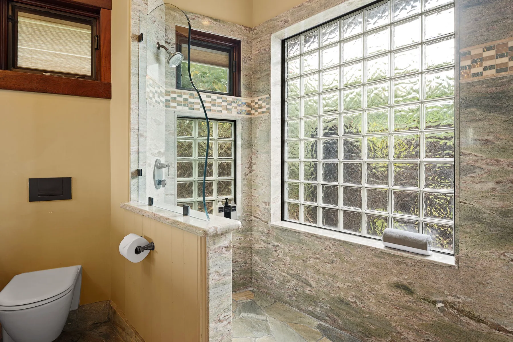 Un baño con una ducha de vidrio y una gran ventana de bloques de vidrio.