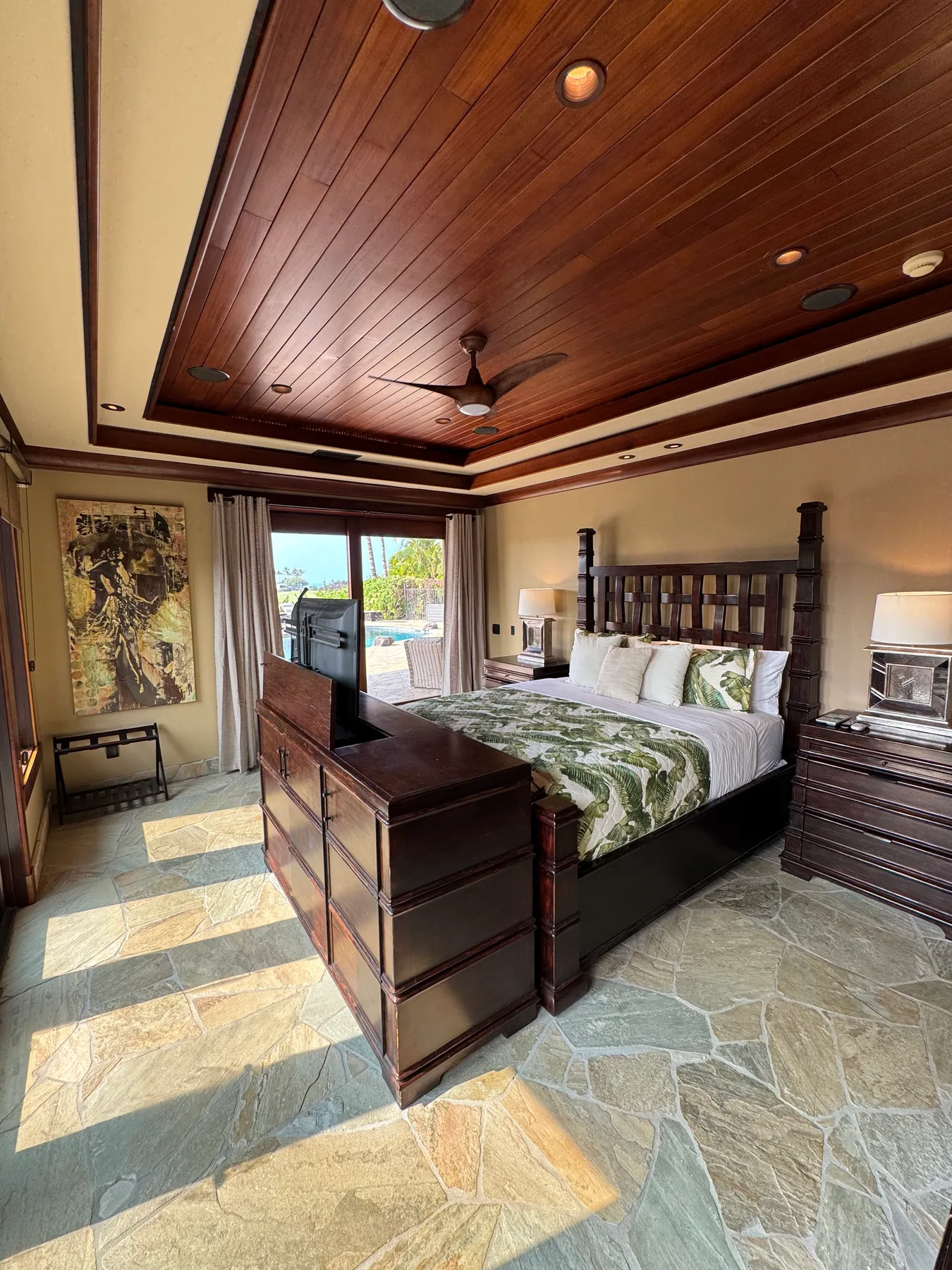 Un dormitorio con una cama grande, muebles de madera oscura y un ventilador de techo.